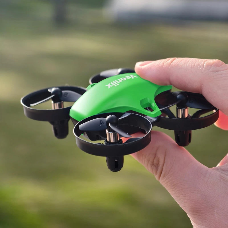 Green mini quadcopter drone with four rotors, held in hand