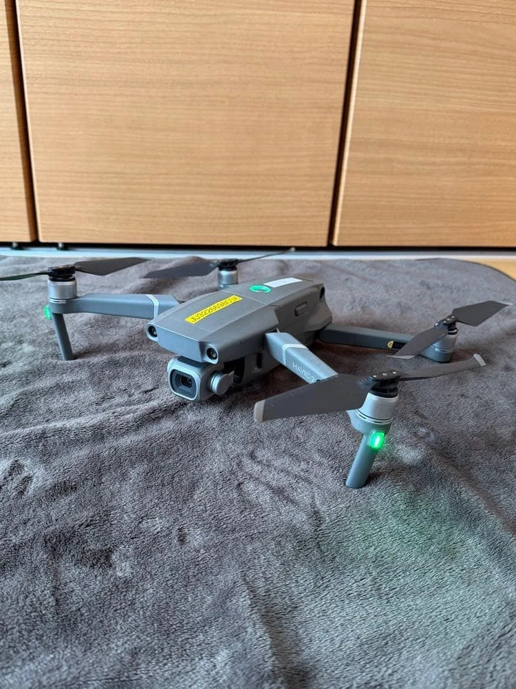 Gray quadcopter drone with four propellers and green status lights