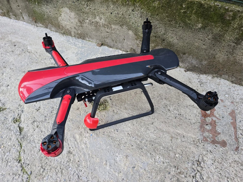 Red and black quadcopter drone with four propeller arms and front camera module
