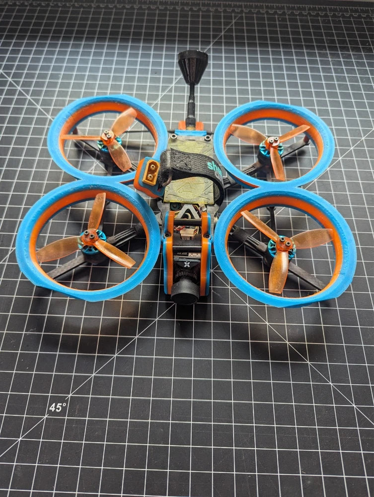 3-inch quadcopter cinewhoop with blue ducts and orange propellers, compact frame