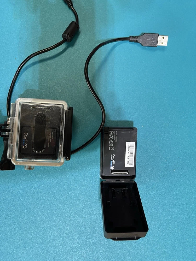 GoPro action camera in clear housing with battery pack and USB cable