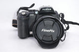 Black Fujifilm FinePix digital camera with attached lens cap and strap