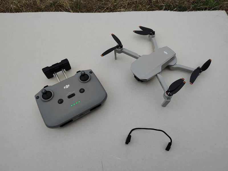 DJI Mini 2 SE camera drone and gray controller with green status lights