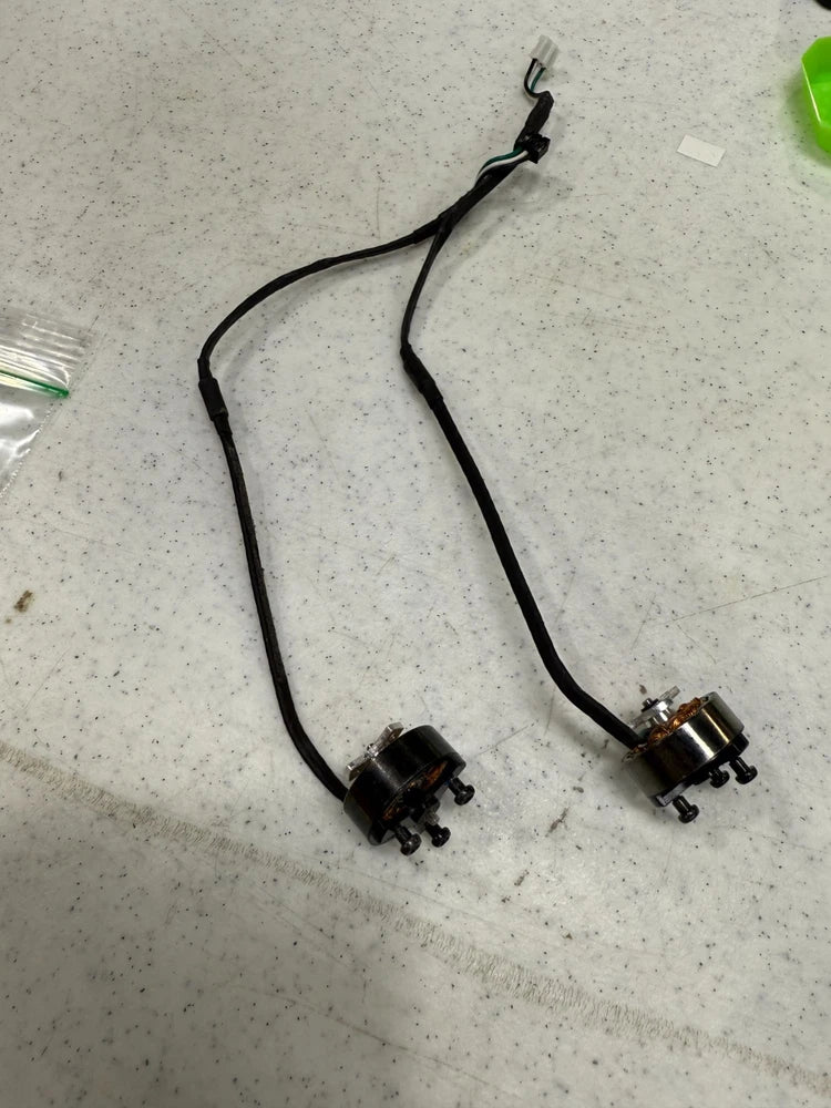 Pair of small brushless DC drone motors with black wires and metal connectors