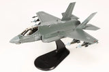 Gray-green F-35A fighter jet model on display stand, front-left view