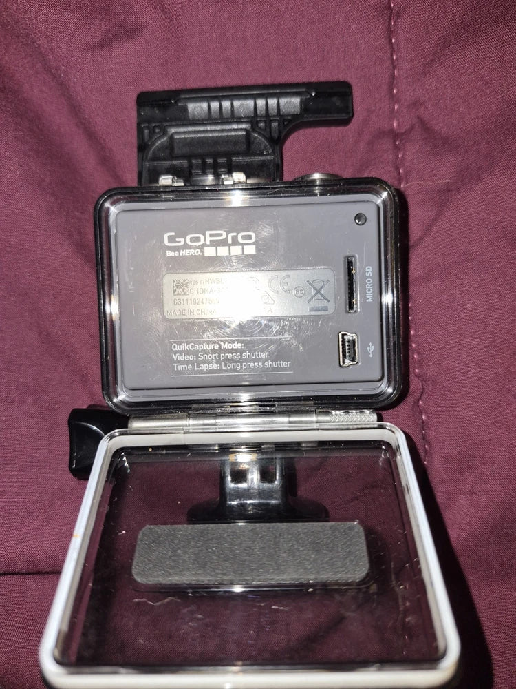 GoPro HERO action camera in open case, showing rear label and ports.