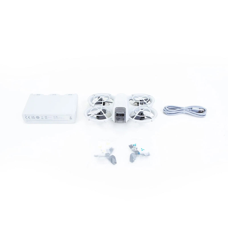 Compact drone kit with white quadcopter, propellers, USB cable, and accessories.