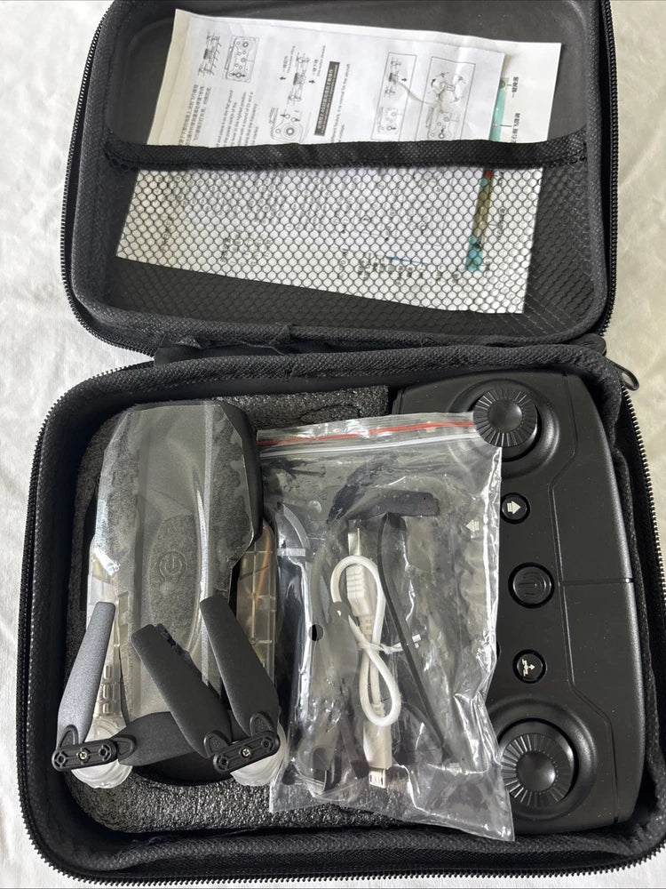 Open zippered carrying case with foldable RC drone, remote, and spare parts