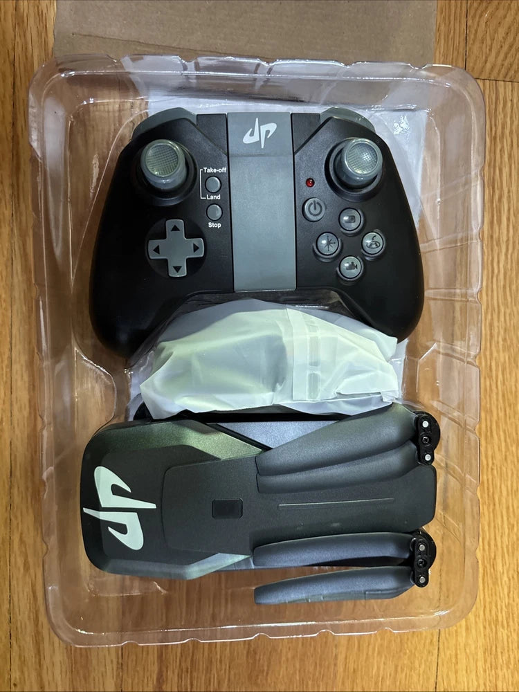 Foldable quadcopter drone with black controller, partially unfolded in plastic packaging
