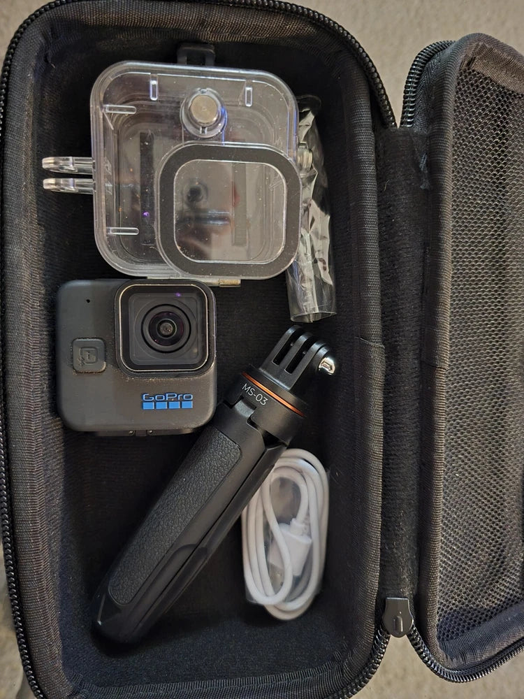 Black action camera in clear waterproof housing with mounts and cable in zippered case