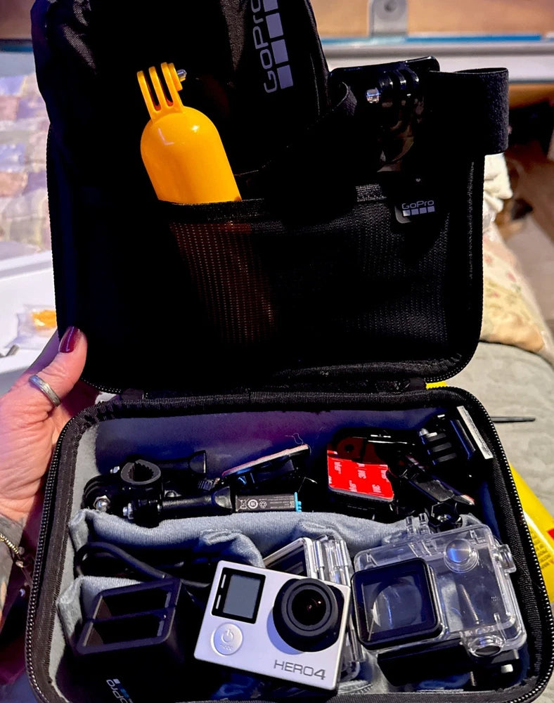 Open black action camera case with HERO4 camera, battery, charger, mounts