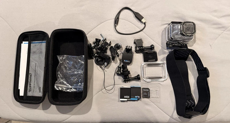 Action camera accessory kit with black camera, case, strap, mounts, batteries, and housing