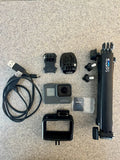 Black action camera bundle with GoPro camera, mounts, cable, battery case, and protective housing