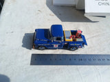 Blue die-cast battery service pickup toy with open bed and small figures, front view