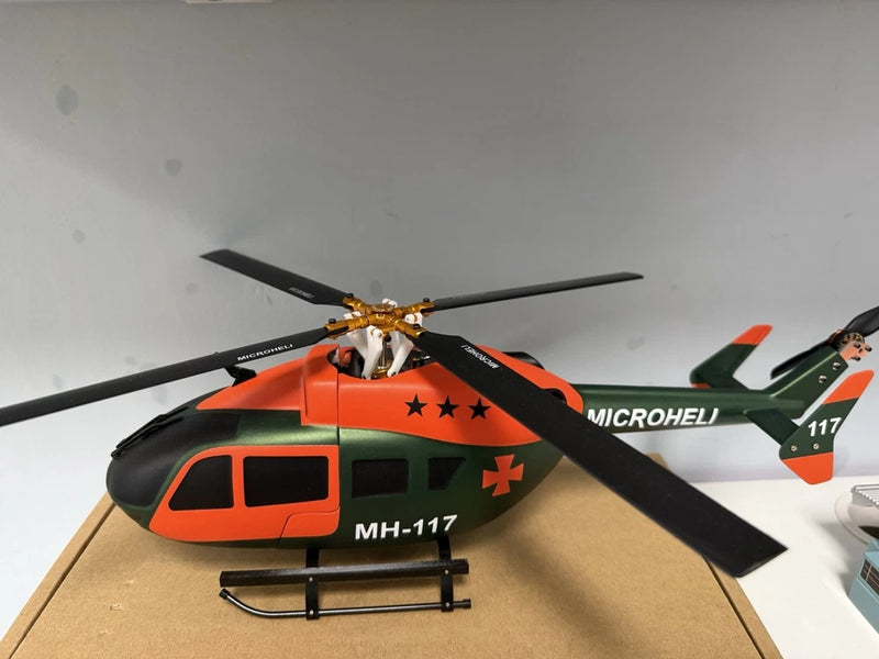 RC scale helicopter model with orange and black fuselage, rotor blades and landing skids