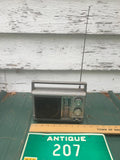 Vintage portable AM/FM transistor radio with speaker grille and green tuning dial