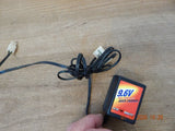 Compact black 9.6V quick battery charger with connected power cable and indicator label