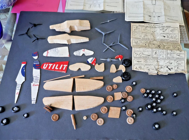 Wood and plastic model airplane kit with spare parts and folded instruction sheets