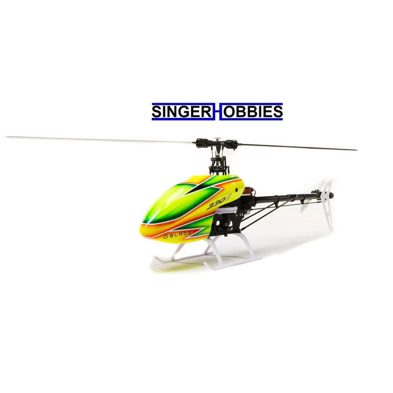 Radio control helicopter with green/yellow body, black rotor head, and white skids