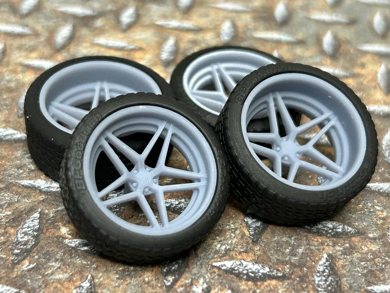 Three model car wheels with black tires and silver five-spoke rims