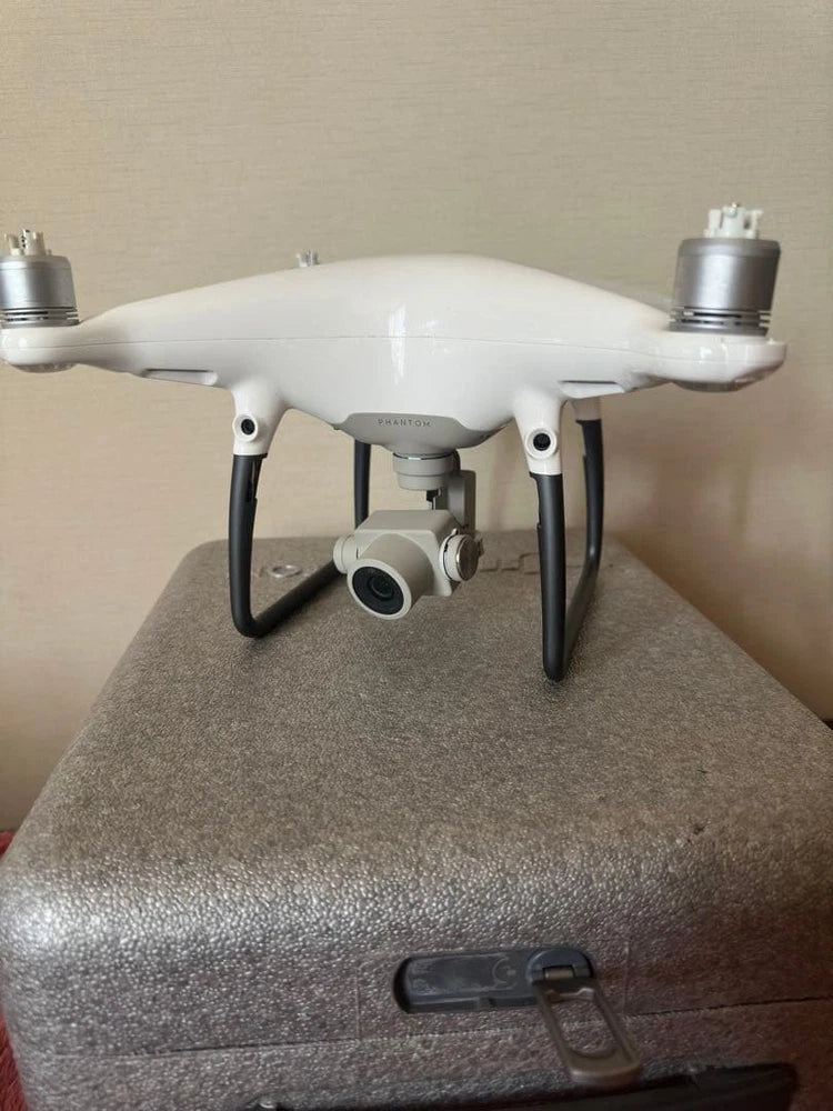 White quadcopter drone with front camera gimbal and four landing legs, power ports visible