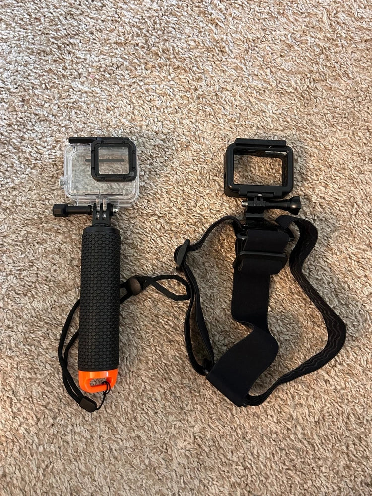 Action camera in clear protective housing with black handle and wrist strap