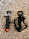 Action camera in clear protective housing with black handle and wrist strap