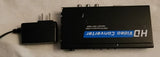 Black HDMI switch converter box with visible front label and attached power adapter