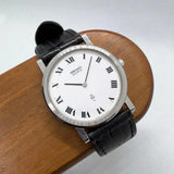 Round analog Seiko Quartz watch with white dial, Roman numerals, black leather strap.