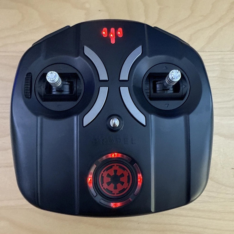 Black remote controller with red LED display and circular trigger button controls
