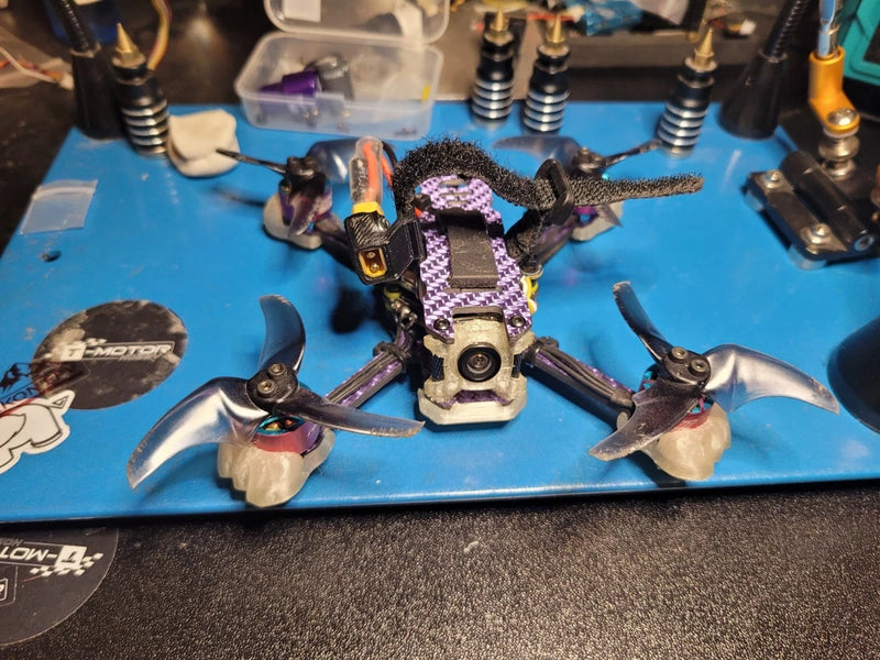FPV racing drone with four motor mounts and central flight controller, black and purple