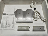 Gray Wii Remote charging dock with two battery covers and attached power cord