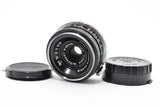 Black Nippon Kogaku Nikkor camera lens with front element and two caps