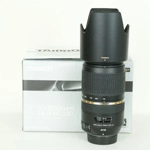 Nikon F-mount telephoto zoom lens with black barrel and gold scale, plus box